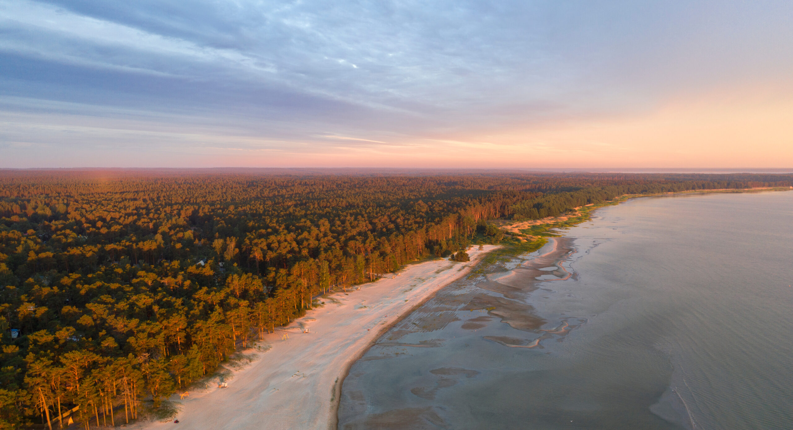 Aerial view on the desolated early morning sunrise coloured sand beach.